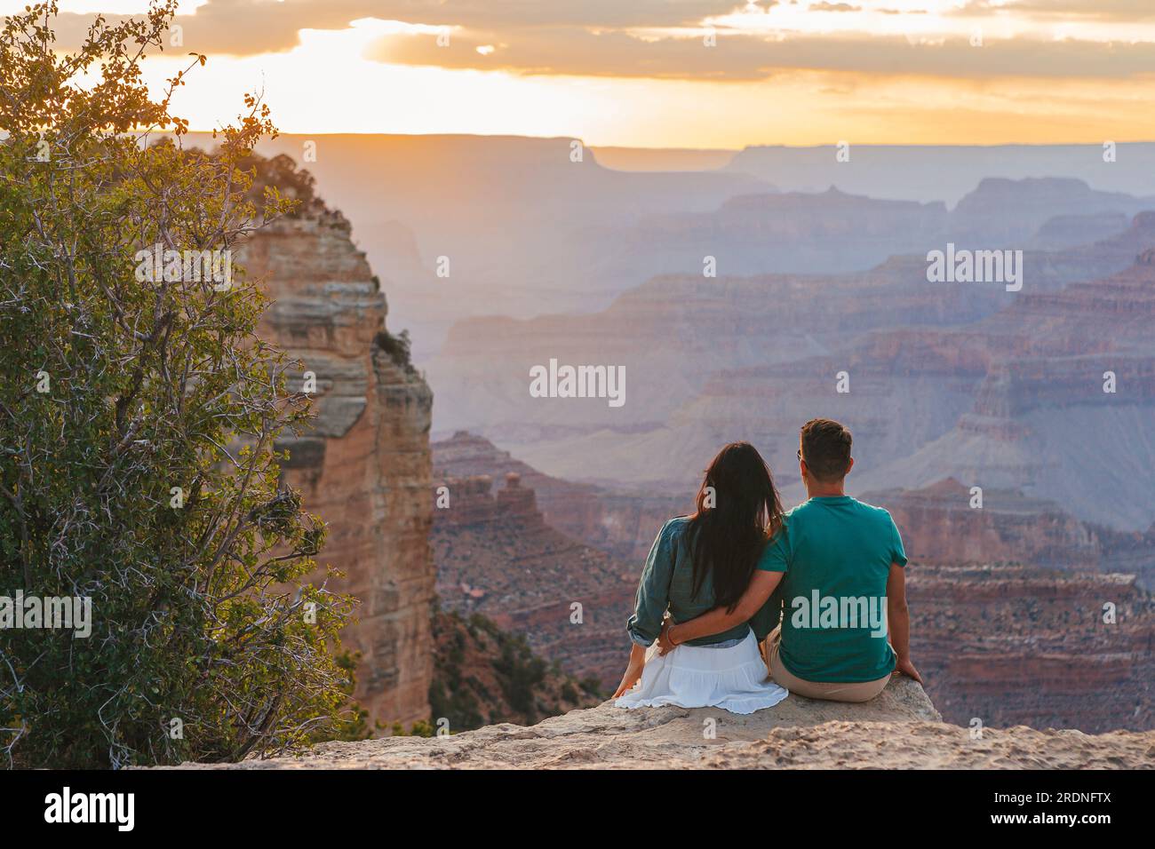 Ein junges Paar auf einer steilen Klippe, das den fantastischen Blick über den berühmten Grand Canyon bei schönem Sonnenuntergang im Sommer im Grand Canyon-Nationalpark in Arizona genießt. Stockfoto