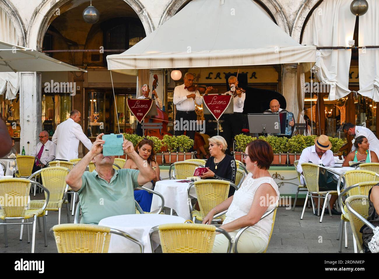 Das Caffè Lavena ist ein historisches Kaffeehaus, das 1750 auf dem berühmten Markusplatz errichtet wurde und im Sommer mit Touristen in Venedig, Venetien, Italien, unterwegs ist Stockfoto