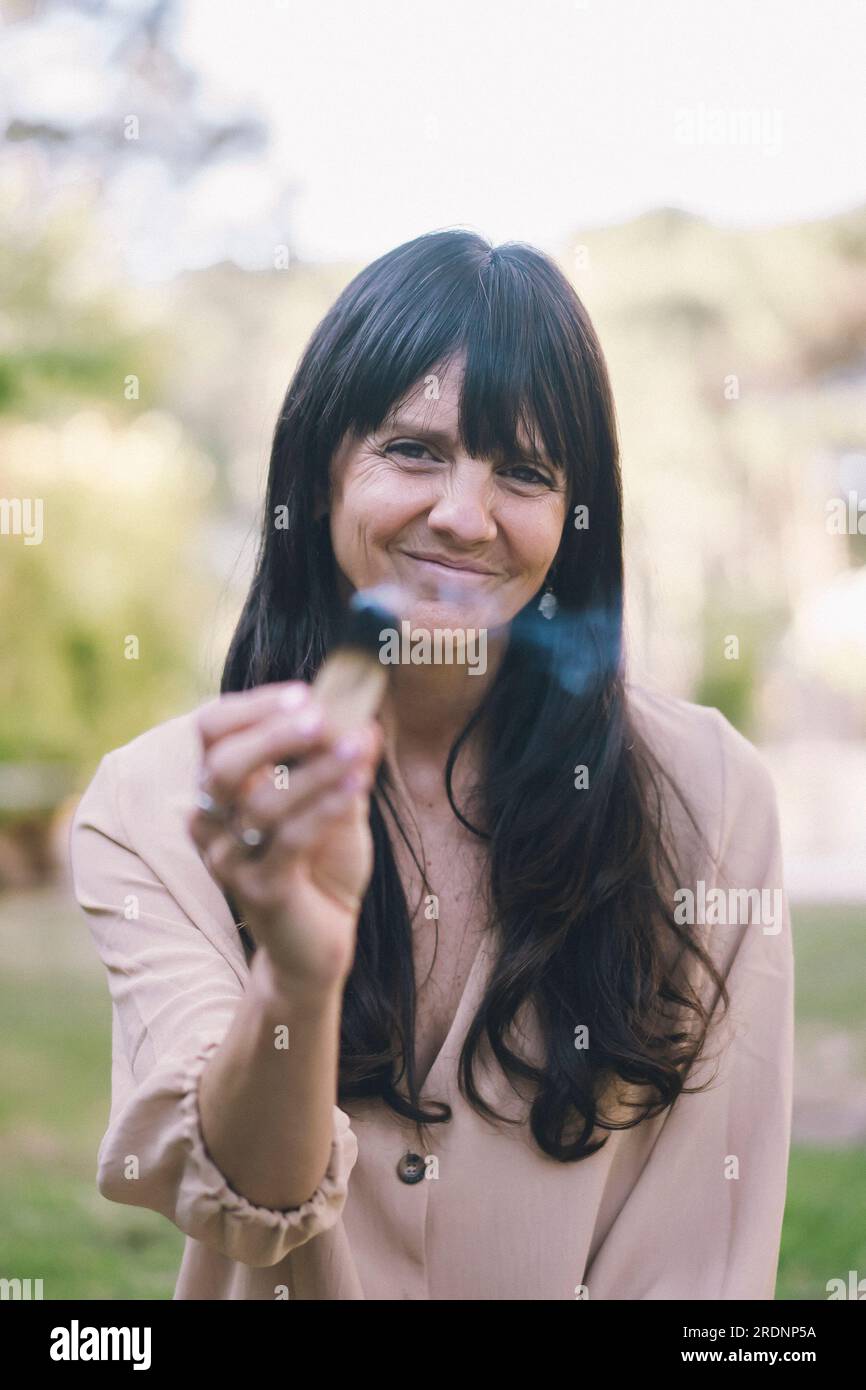 Eine Frau mit langen Haaren, die einen brennenden palo santo oder einen heiligen Baum hält. Stockfoto