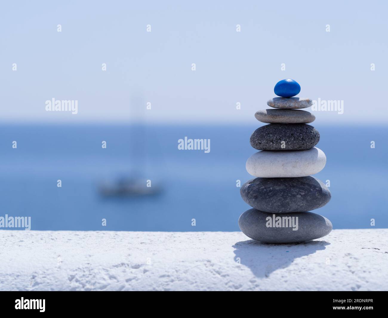 Rock Zen Pyramide aus bunten Kieseln vor dem Hintergrund des Meeres und des Bootes. Konzept von Lebensgleichgewicht, Harmonie und Meditation Stockfoto