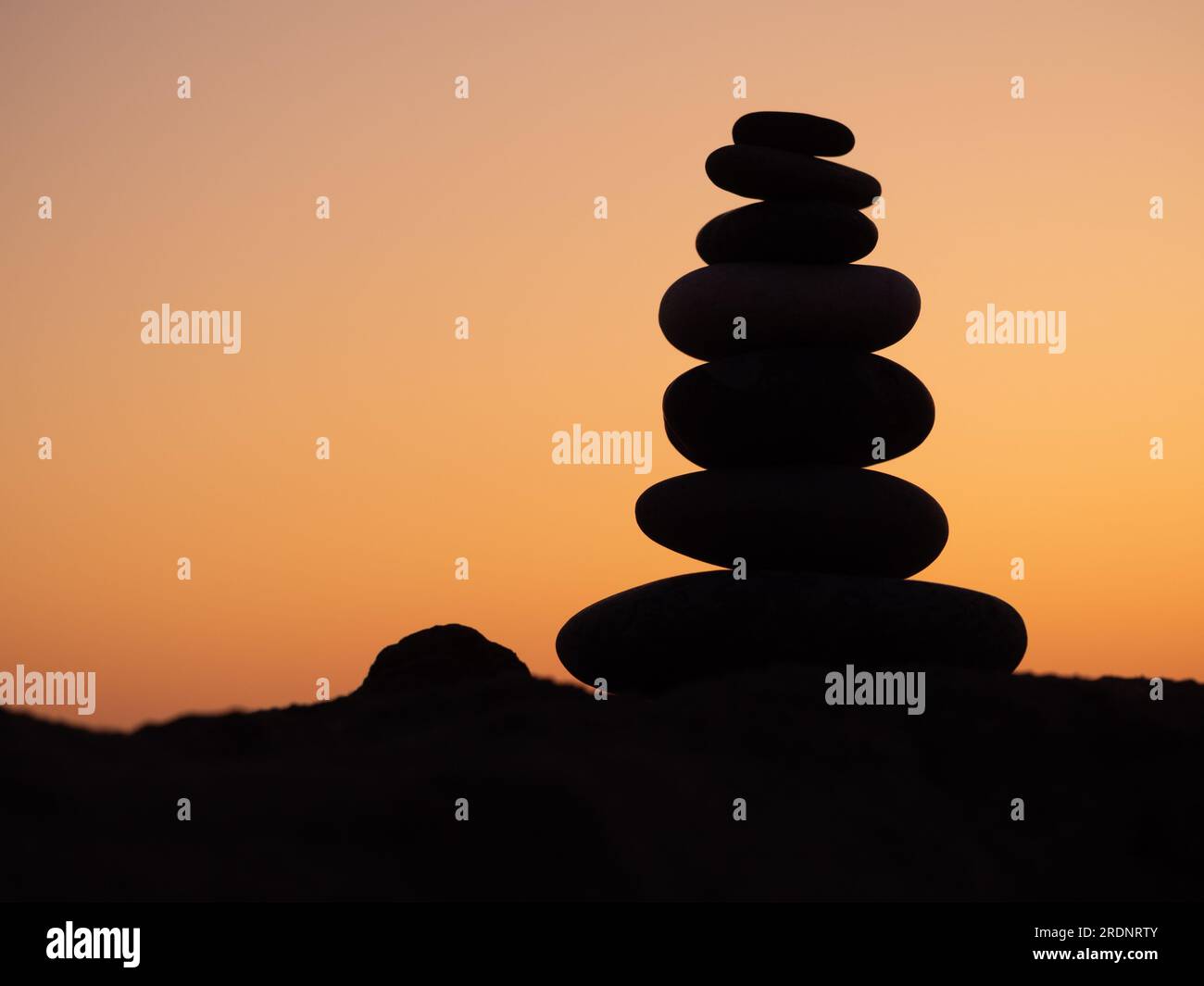 cairn bei Sonnenuntergang, Steinbalancen, Steinpyramide bei Sonnenuntergang, Konzept der Lebensbilanz, Harmonie und Meditation Stockfoto