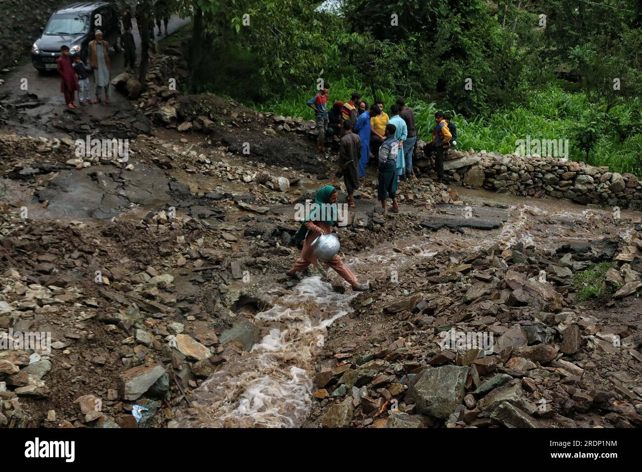 Srinagar, Kaschmir. 22. Juli 2023 22. Juli 2023, Srinagar Kaschmir, Indien: Eine Frau überquert eine beschädigte Straße nach Überschwemmungen im Gebiet von Faqir Gujri, am Stadtrand von Srinagar. Die Einheimischen behaupteten, dass mehrere Häuser Risse entwickelten und Maisfelder beschädigt wurden, es wurden jedoch keine Todesfälle gemeldet. Mehrere Regionen von Jammu und Kaschmir sind von anhaltenden starken Regenfällen heimgesucht worden, die zu mehreren Erdrutschen in den hügeligen Gebieten geführt haben und zur Schließung des Nationalautobahn Jammu-Srinagar geführt haben. Kredit: Eyepix Group/Alamy Live News Stockfoto