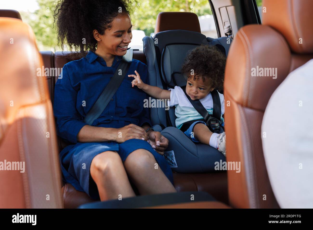 Junge lächelnde Mutter und ihr kleiner Sohn sitzen zusammen auf dem Rücksitz eines Taxis Stockfoto