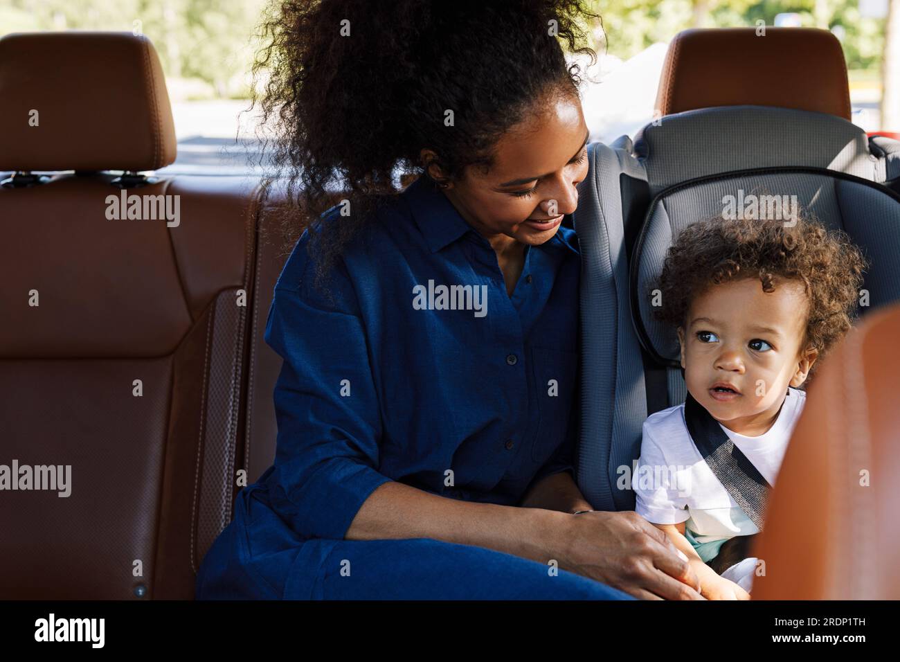 Lächelnde Mutter, die ihren kleinen Sohn ansah, während sie auf dem Rücksitz des Taxis saß Stockfoto