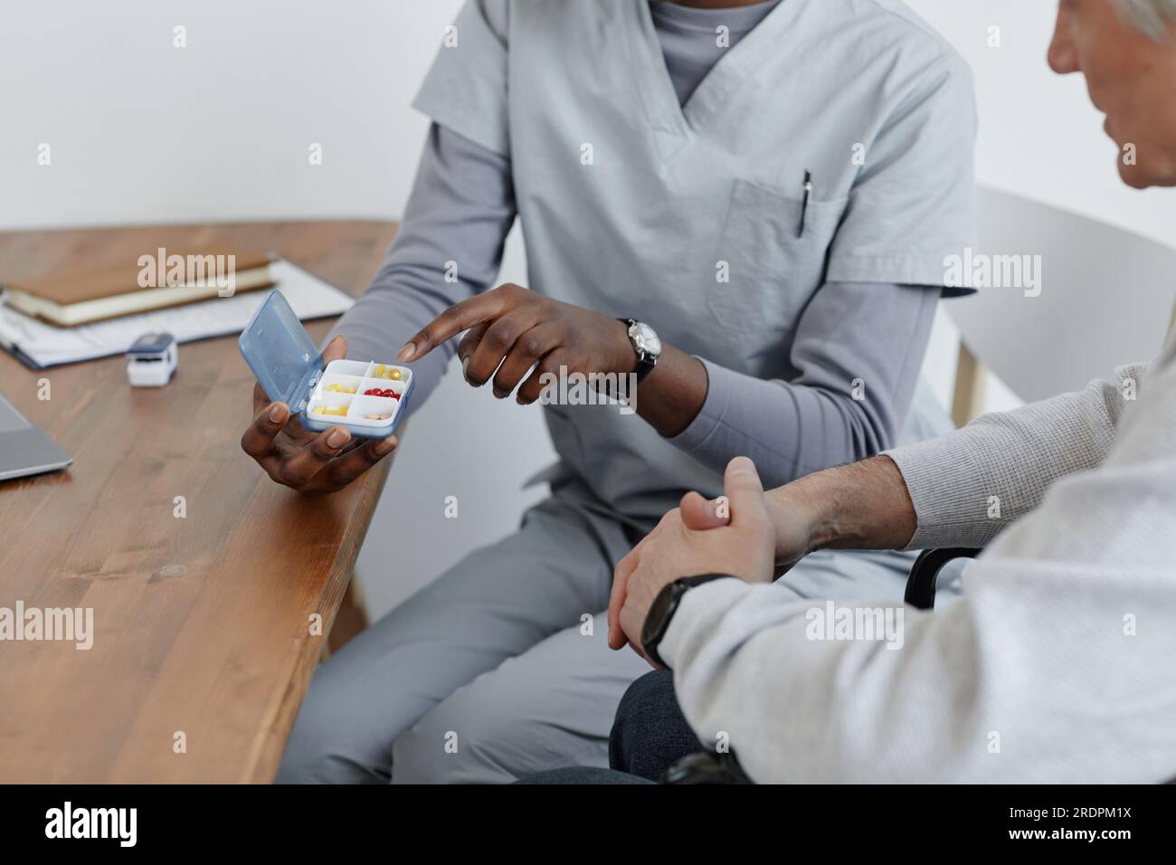 Nahaufnahme einer nicht erkennbaren Krankenschwester, die dem Seniorenmann im Seniorenheim den Medizinplan erklärt Stockfoto
