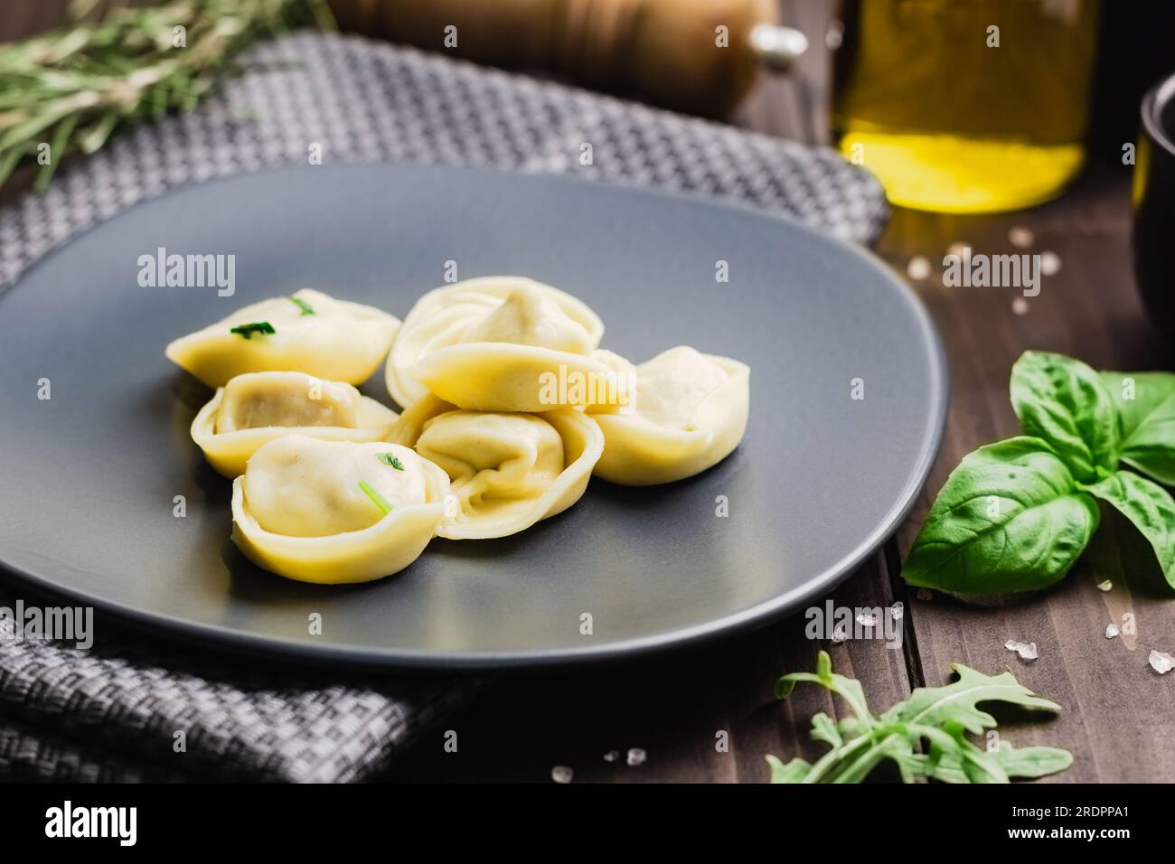 Ravioli mit Basilikum und gemahlenem Pfeffer. Winterrezepte für die kalte Jahreszeit mit italienischer Küche, Blick auf die Vorderseite mit Holzhintergrund Stockfoto