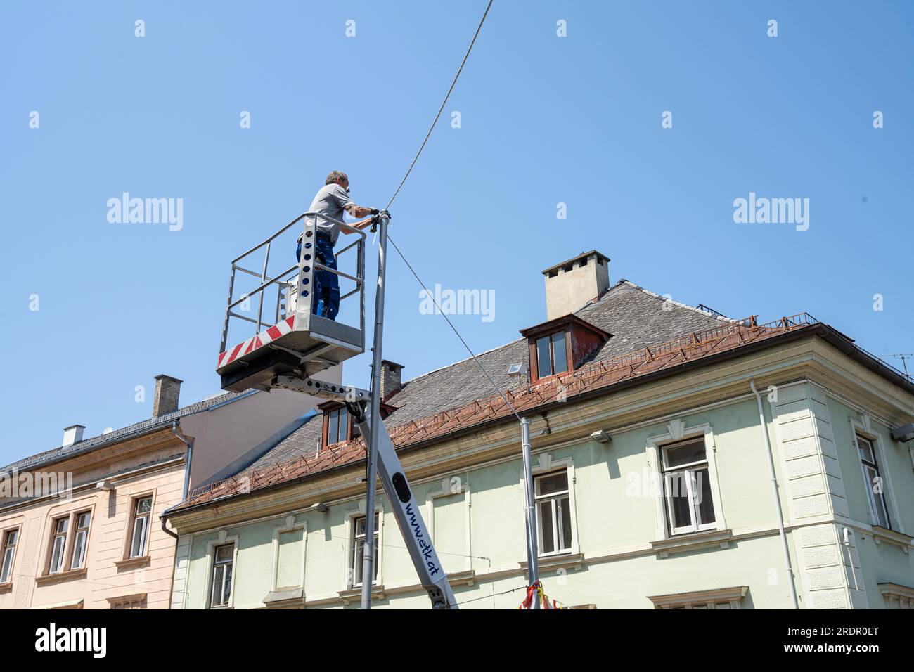 Villach, Österreich. Juli 18 2023. Ein Techniker hob auf einem Korb, während er an Elektrokabeln in einer Straße im Stadtzentrum arbeitete Stockfoto