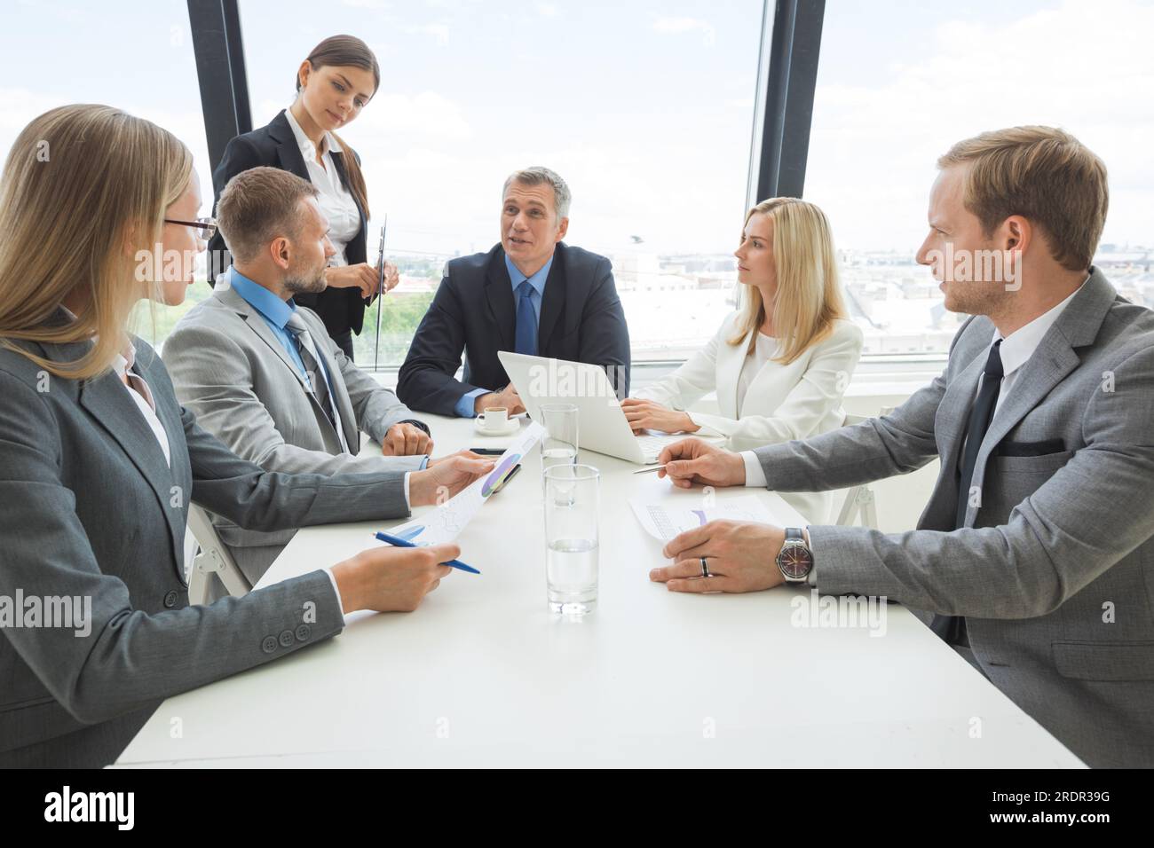 Gemischte Gruppe von Angestellten an der Sitzung Dokumente diskutieren Stockfoto
