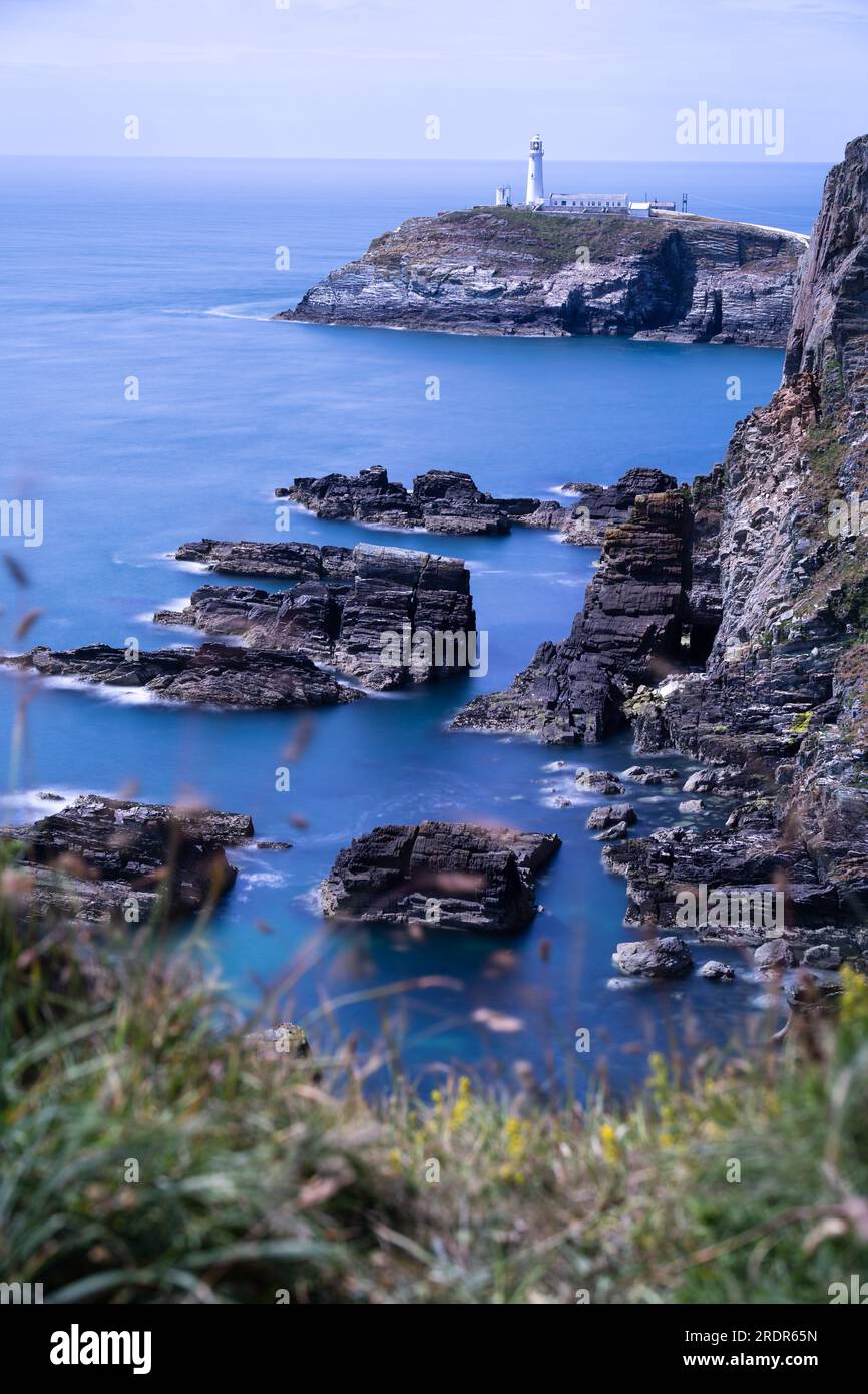 South Stack Lighthouse in Wales. Blaues Meer. Lange Belichtung. Glattes Meer. Verschwommenes Gras im Vordergrund. Stockfoto