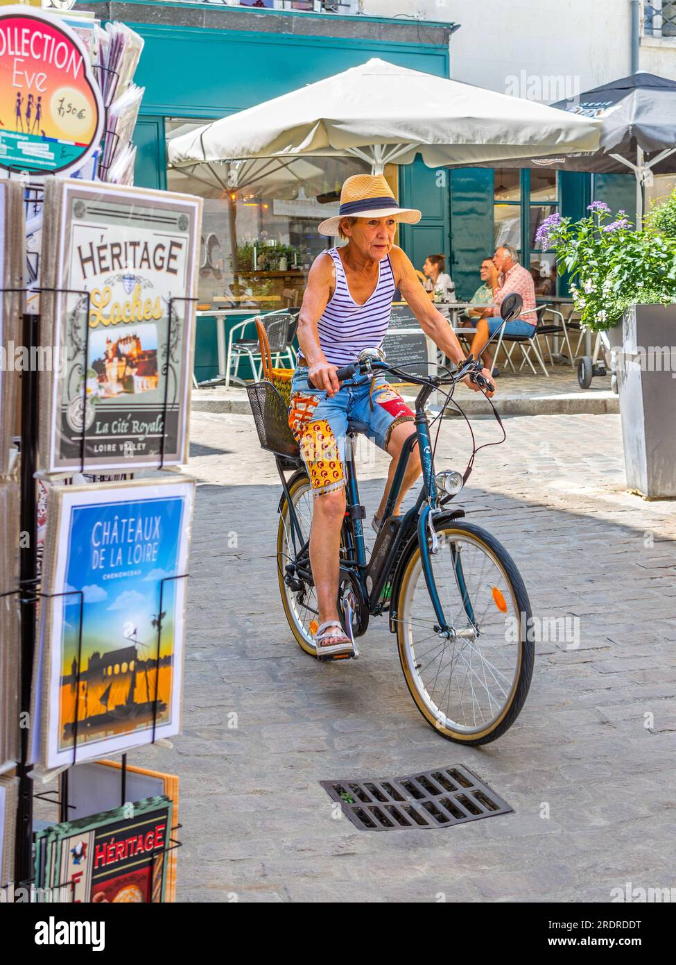 Reife Frau, lässig gekleidet, Radfahrer auf dem Nakamura E-Bike entlang der engen Straße - Loches, Indre-et-Loire (37), Frankreich. Stockfoto