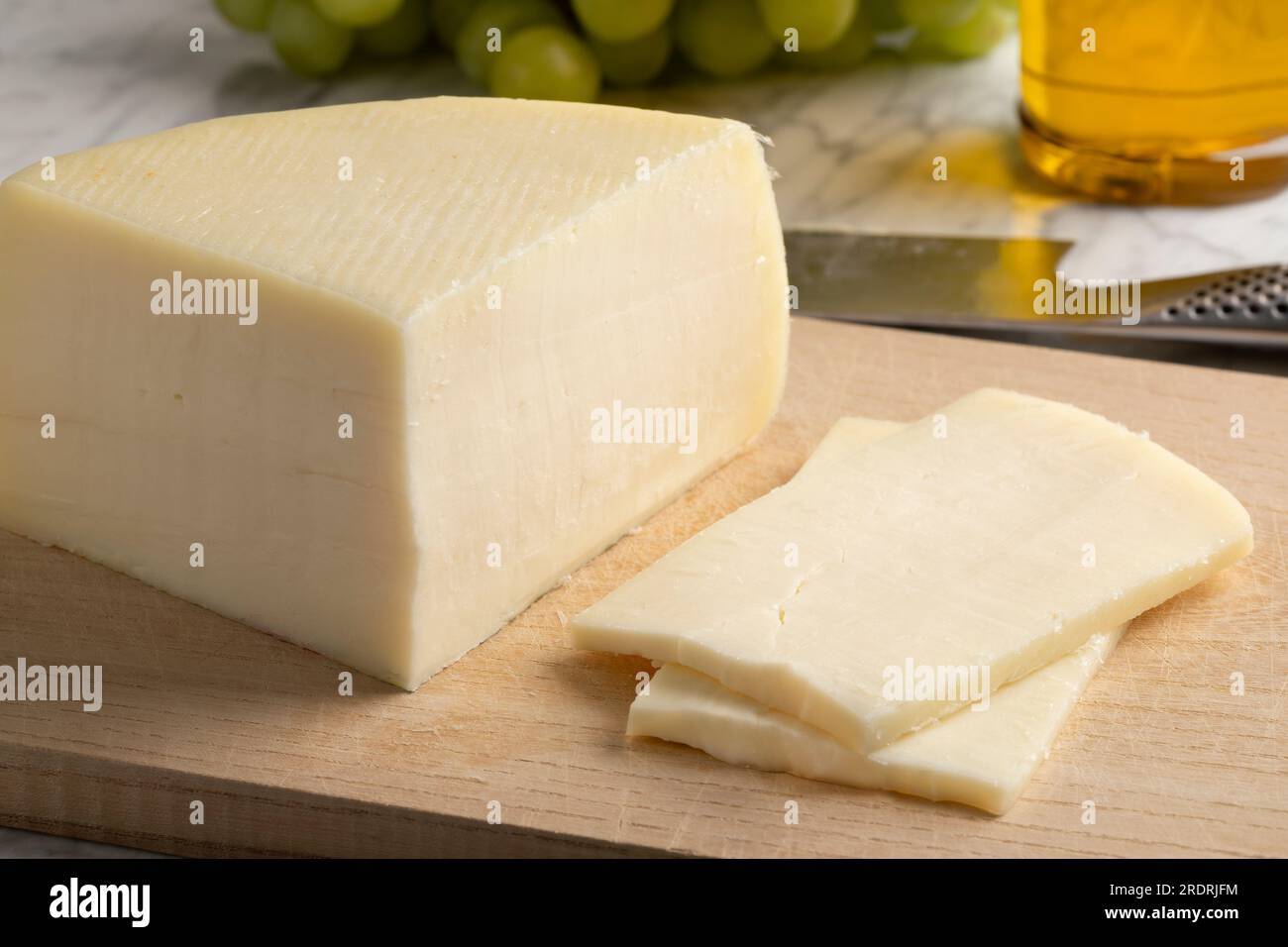 Ein Stück handgefertigter halbweicher italienischer Bel Paese-Käse und Scheiben auf einem Schneidebrett Stockfoto