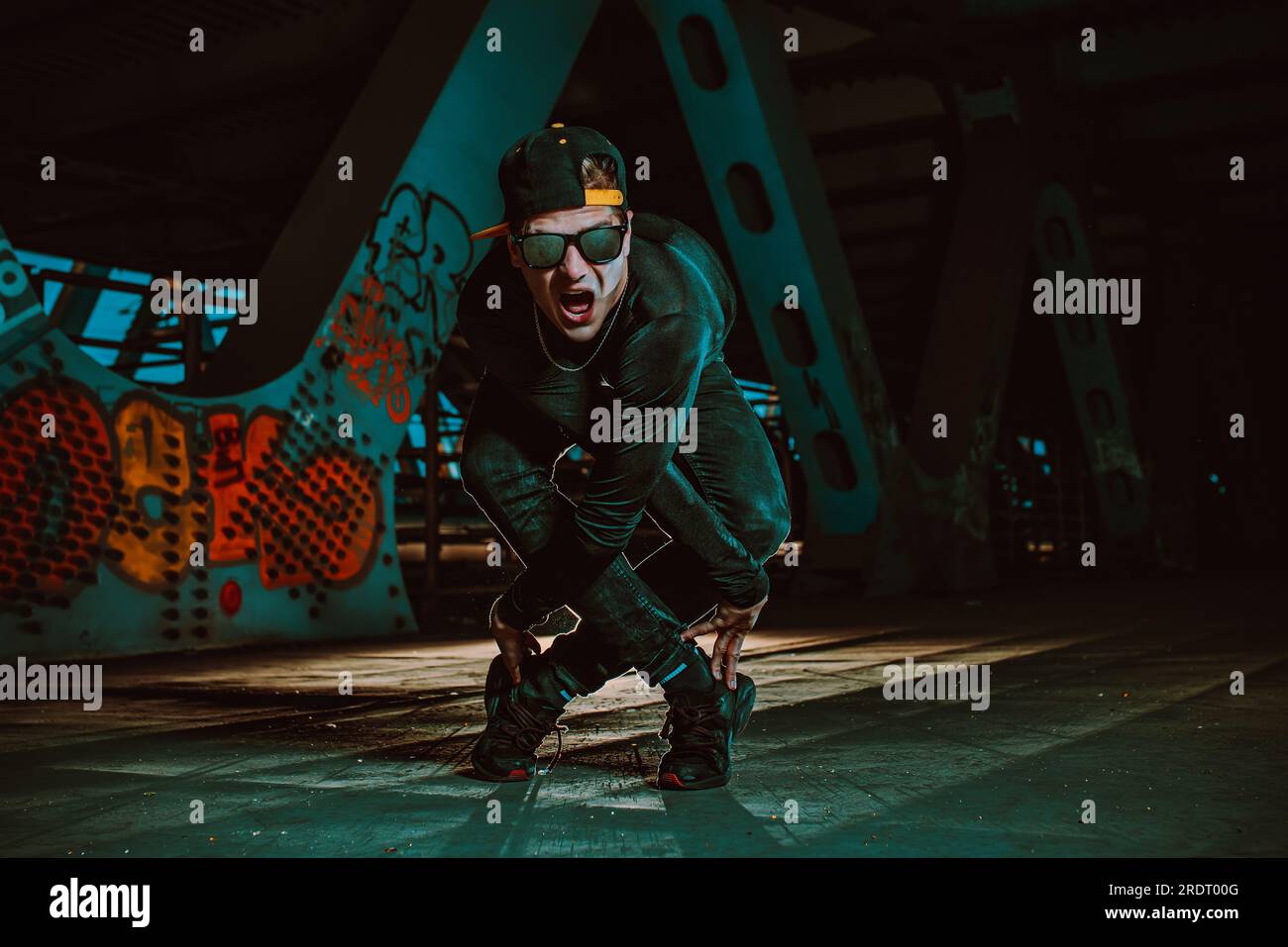 Ein junger, cooler Mann, der nachts auf einer Stadtbrücke posiert Stockfoto