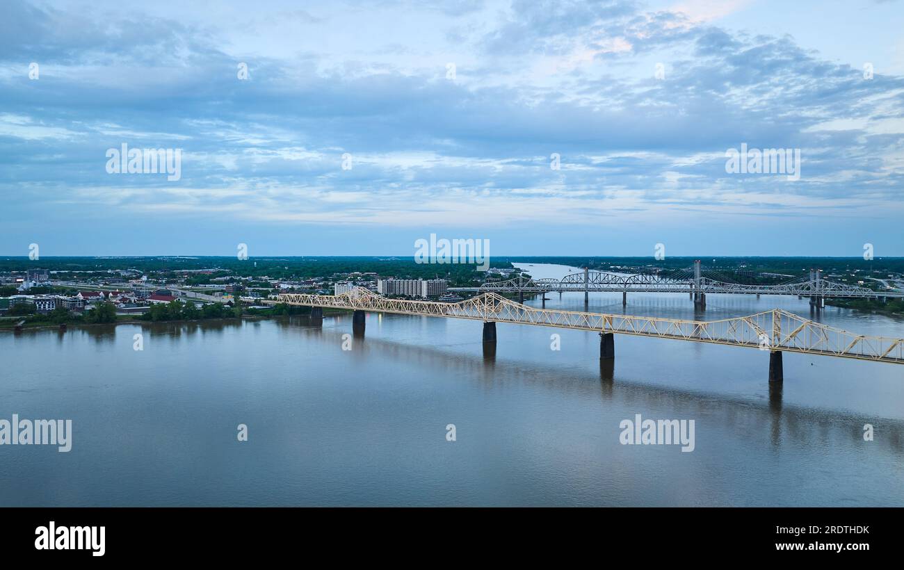 Hängebrücken über den blauen Fluss unter tiefblauem Himmel führen zu einer grünen Landflugbahn Stockfoto