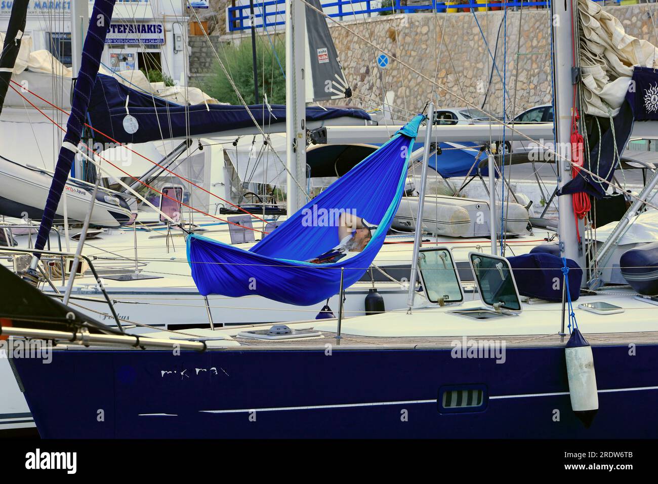 Mann schläft in einer Hängematte auf einer Yacht im Hafen von Livadia, Insel Tilos, Griechenland, Europa Stockfoto