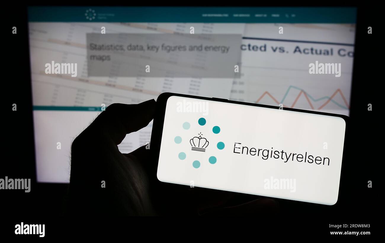 Person, die ein Mobiltelefon mit dem Logo der dänischen Energieagentur Energistyrelsen auf dem Bildschirm vor der Webseite hält. Konzentrieren Sie sich auf das Display des Telefons. Stockfoto