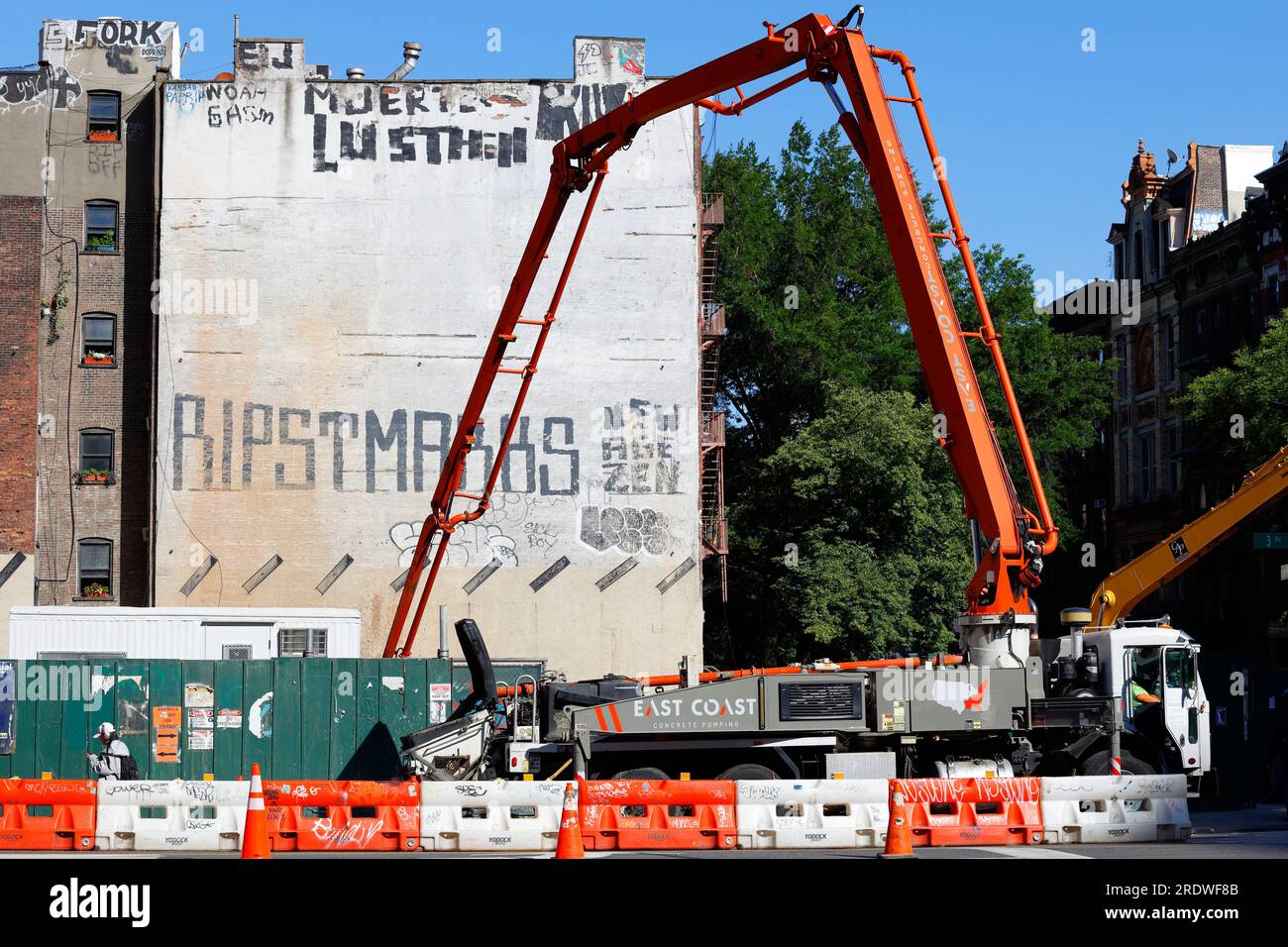 Ein Betonpumpwagen auf einer Baustelle in Manhattan East Village, New York City. Der Pumpenwagen hat einen ausfahrbaren Ausleger für die Reichweite. Stockfoto