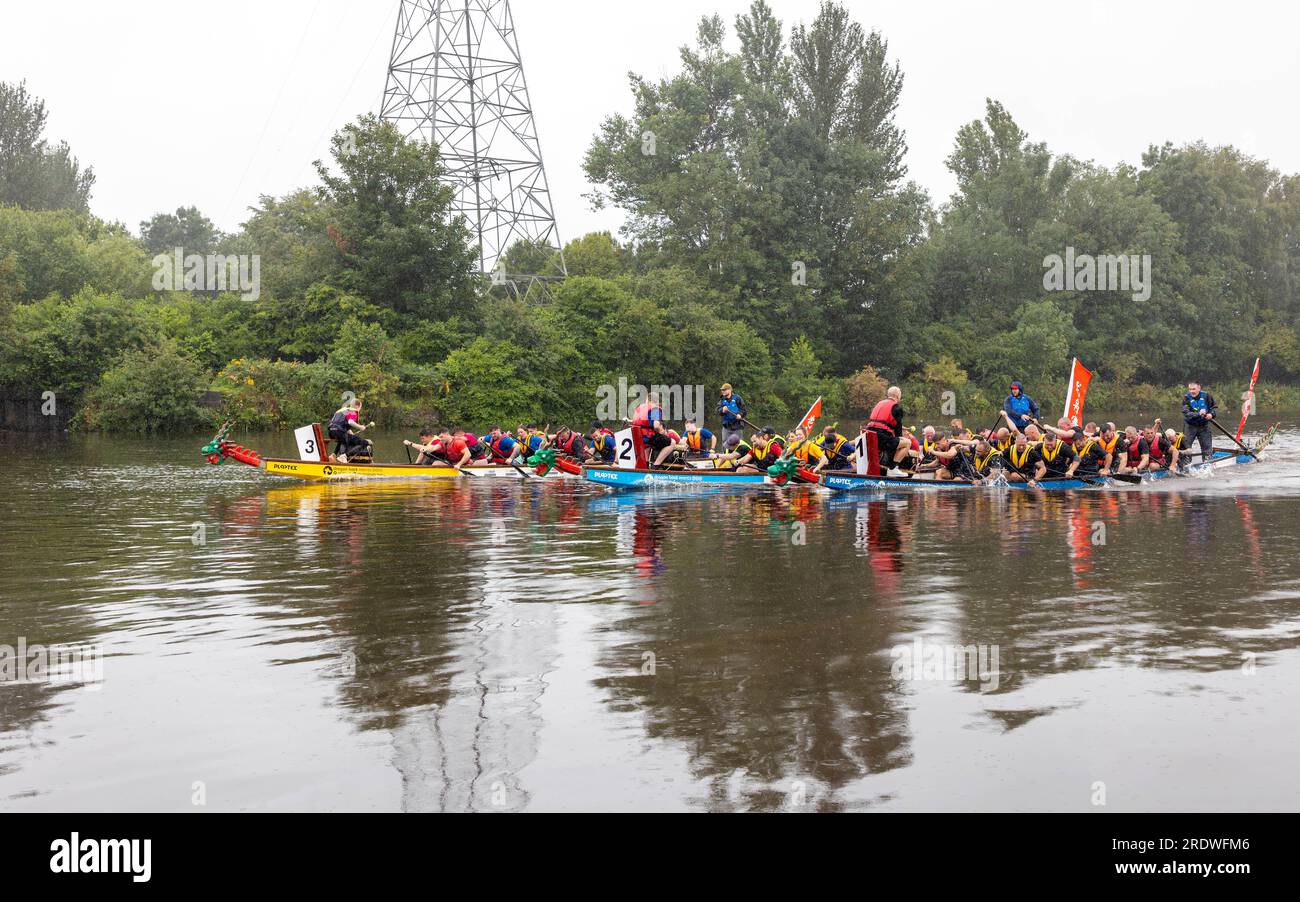23. Juli 2023 - River Mersey, Warrington, Cheshire, England - ein organisiertes Dragon Boat Festival am Fluss Mersey in Warrington. Im Ruderclub und trotz des durchgehend regnerischen Tages wetteiferten sich einige Drachenboote um einen Gewinner. Das Finale war ein sehr knappes Rennen. Ziel der Veranstaltung war es, Gelder für das St. Rocco's Hospice zu sammeln, das es ist, eine hochwertige Versorgung und Unterstützung für Menschen und ihre Angehörigen mit lebenslimitierenden Krankheiten, die in der Region Warrington leben, zu bieten, damit jede Person Komfort, Hoffnung, Kraft und Frieden finden kann. Stockfoto