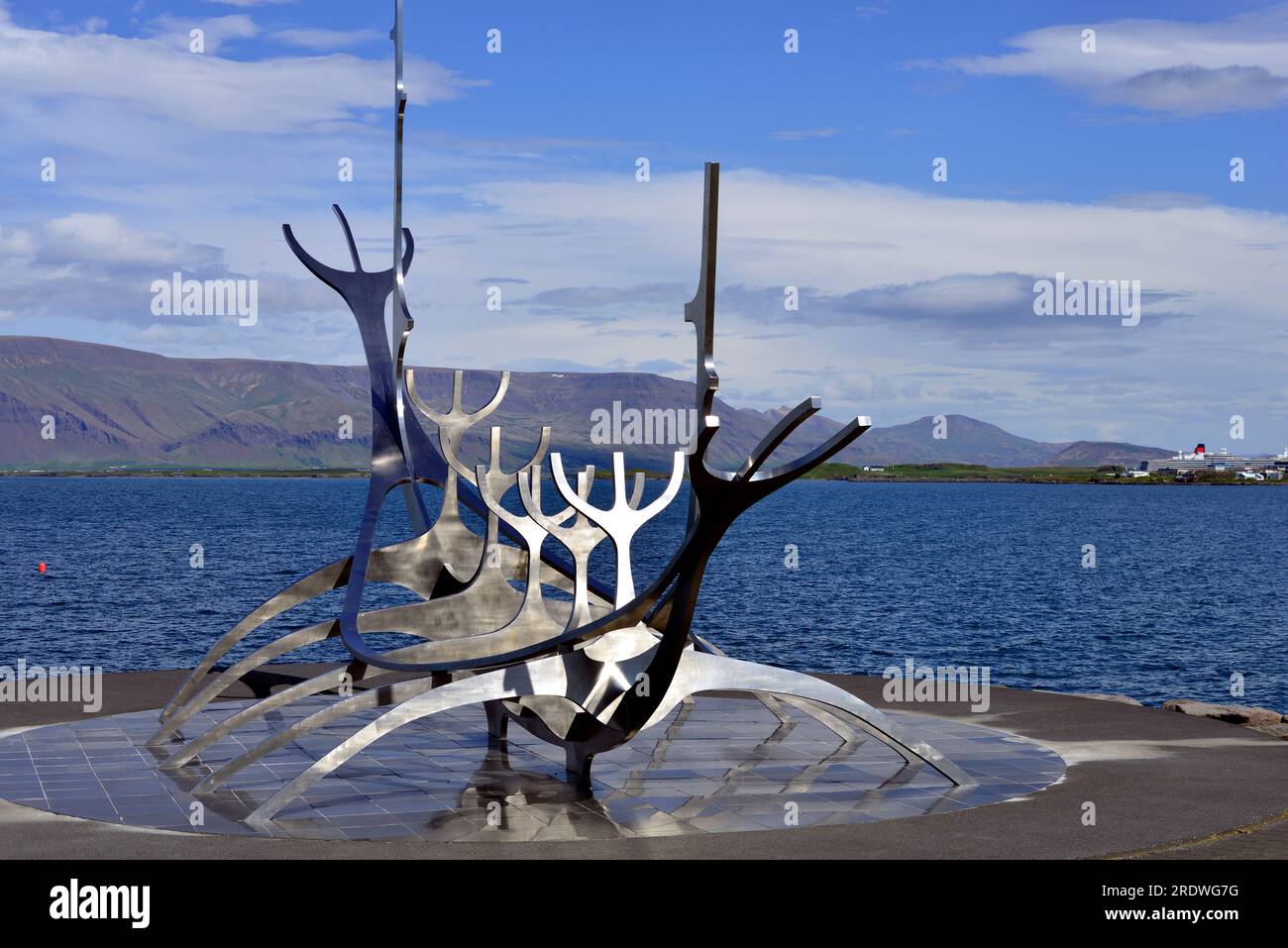 Edelstahlskulptur eines Wikingerschiffs, bekannt als Sun Voyager in Reykjavik Island. Videyjarstofa House kann man in der Ferne sehen. Stockfoto