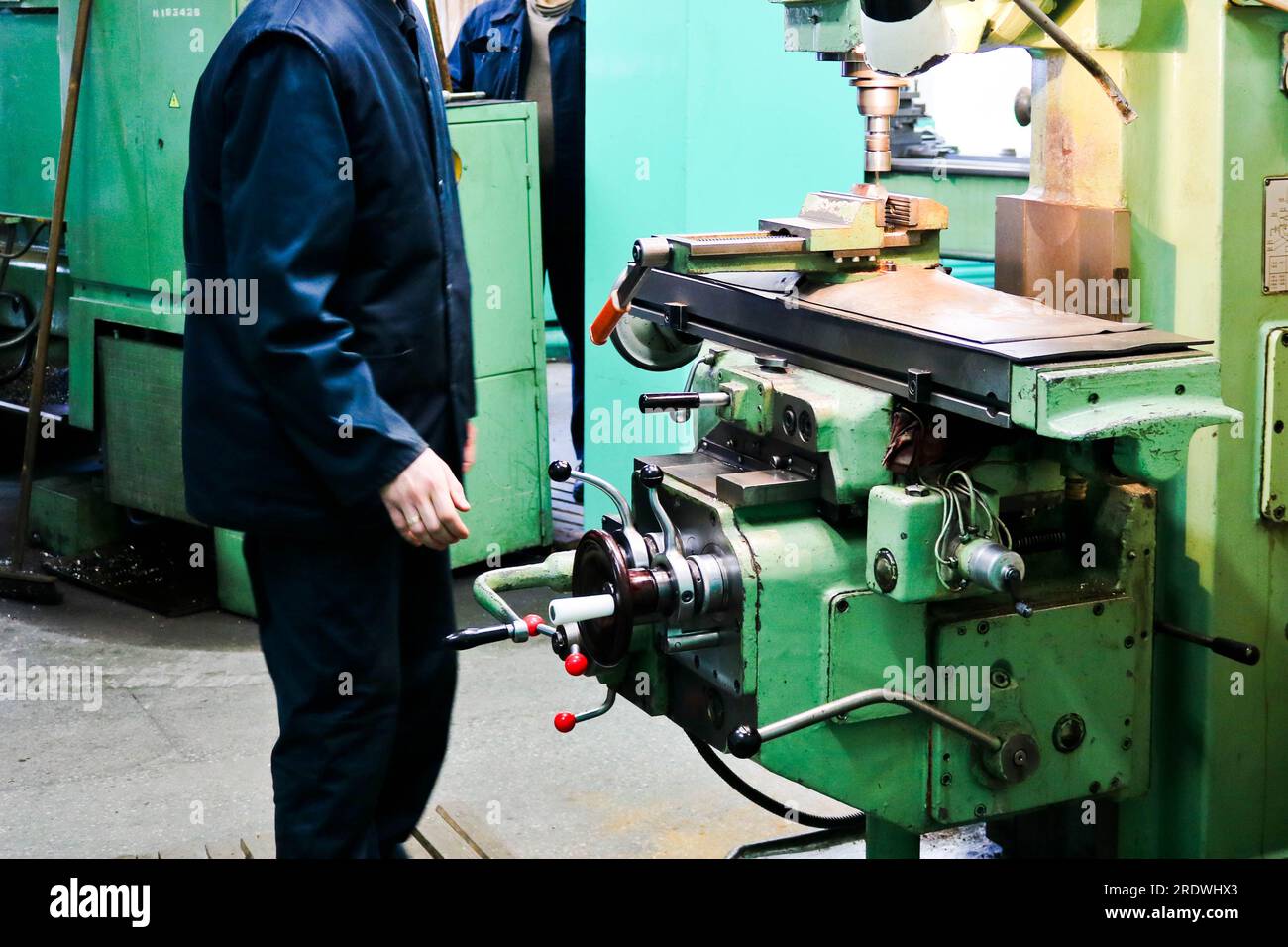 Ein männlicher Arbeiter arbeitet an einer größeren Metallschleusen-Drehmaschine, Ausrüstung für Reparaturen, Metallarbeiten in einer Werkstatt in einer Metallurgieanlage in einem Reparaturprogramm Stockfoto