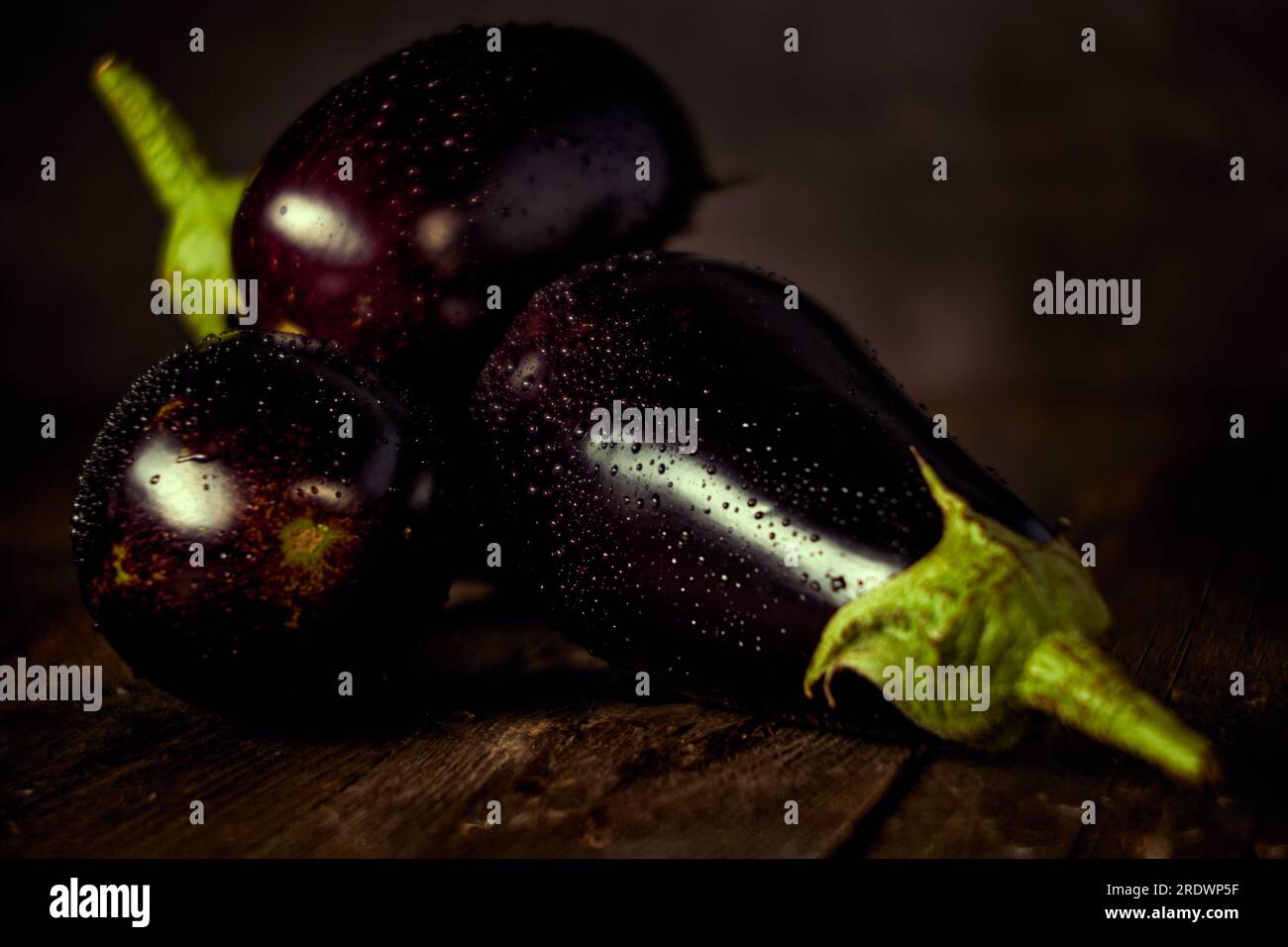 Nahaufnahme mehrerer Auberginen auf Einem Holztisch mit Wassertropfen Stockfoto