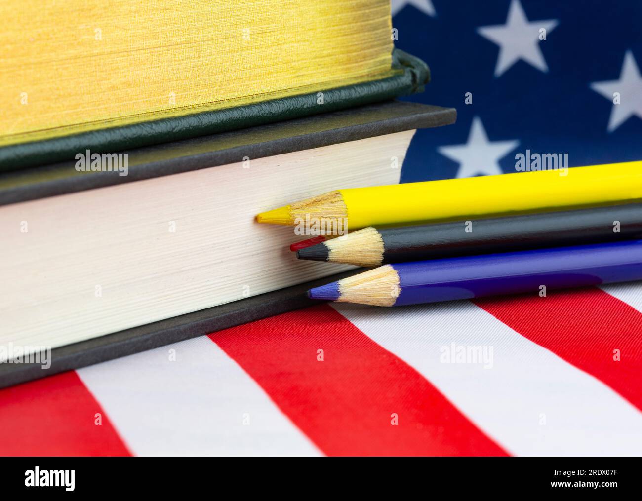 American Education symbolisierte die Nahaufnahme der amerikanischen Flagge mit Büchern und bunten Bleistiften Stockfoto