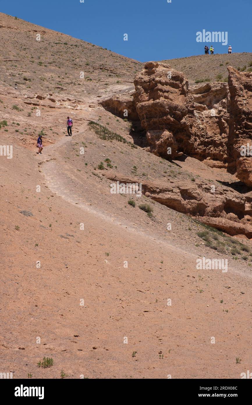 Kasachstan, Charyn (Sharyn) Canyon. Besucher, die vom Canyon Rim den Trail hinunter in den Canyon wandern. Stockfoto
