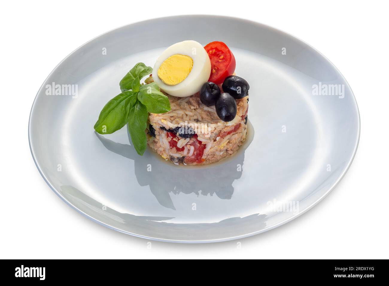 Reissalat mit Thunfisch, Tomaten, Oliven und gekochten Eiern- und Basilikumblättern in perlfarbener Platte, isoliert auf weißem Boden mit Schnittpfad Stockfoto