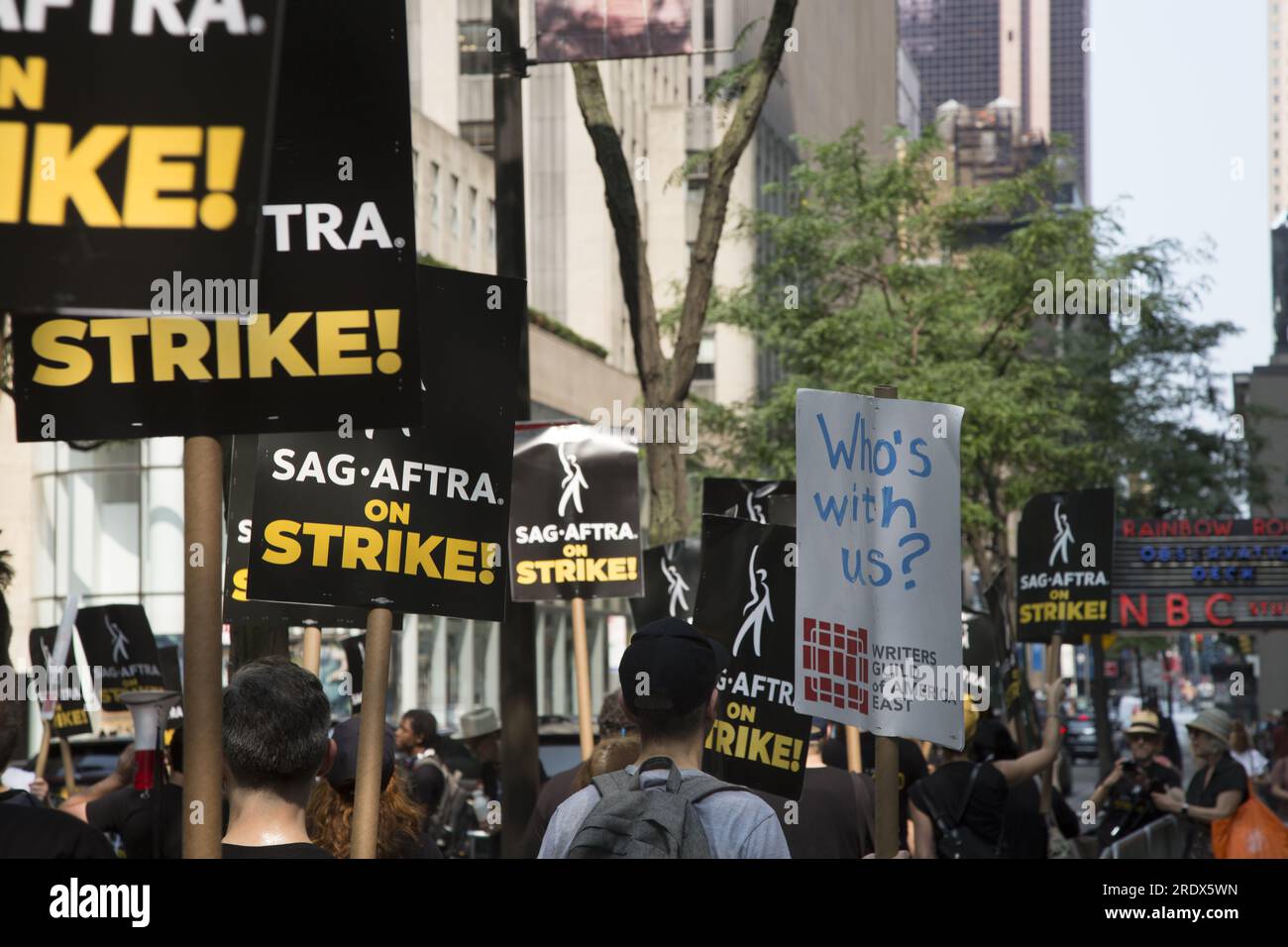 New York City: Der Streik geht weiter unter der Schriftstellergilde von Amerika zusammen mit Mitgliedern der SAG-AFTRA Union mit Streikposten an mehreren Orten in Manhattan. Stürmer demonstrieren vor den NBC Studios auf der W. 49. Street beim Rockefeller Center und lähmen die Unterhaltungsindustrie. Stockfoto