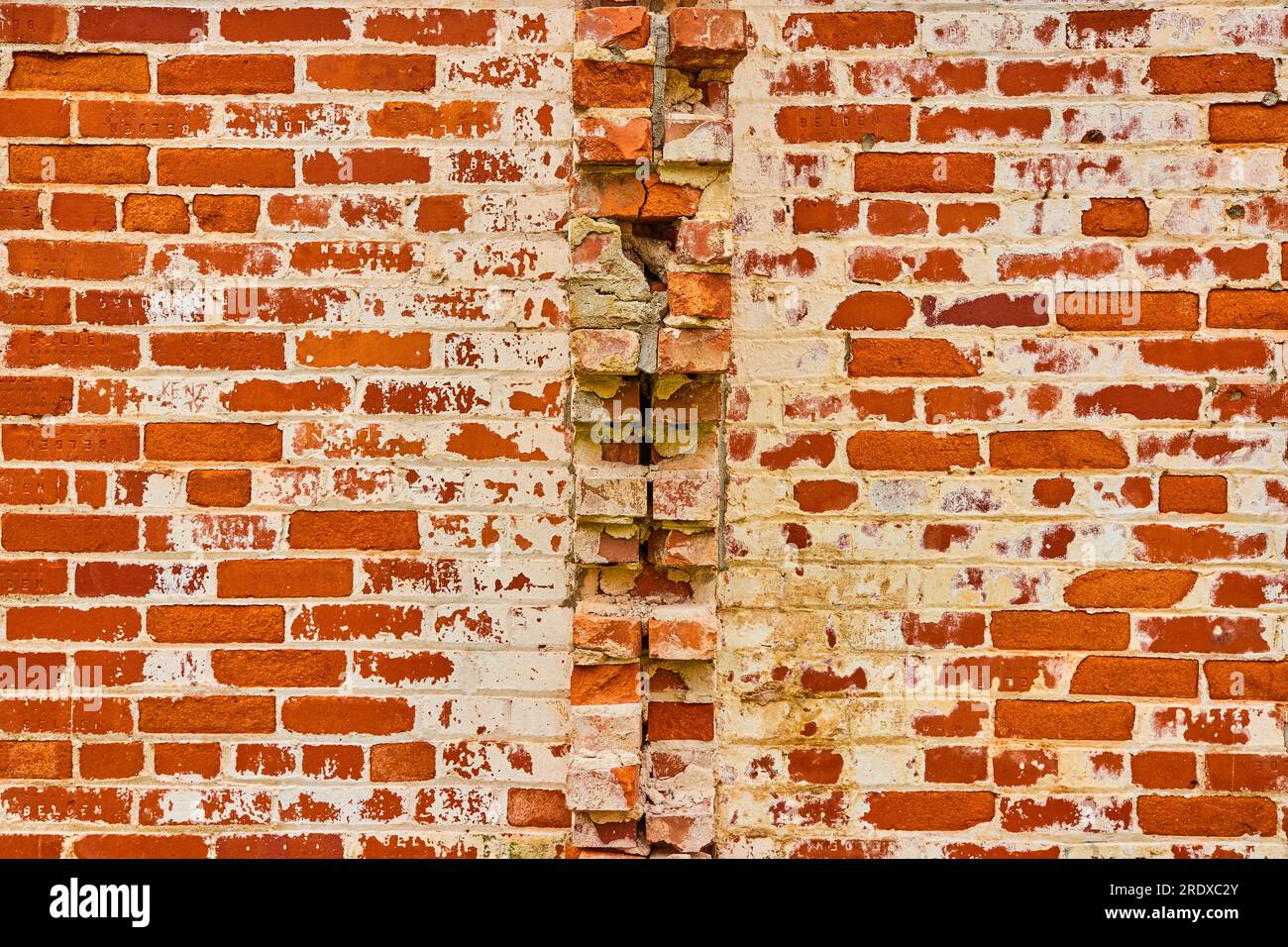 Rote Background Asset Ziegel mit weißem Verfall und kaputte, die aus der Mitte der Wand herausstießen Stockfoto