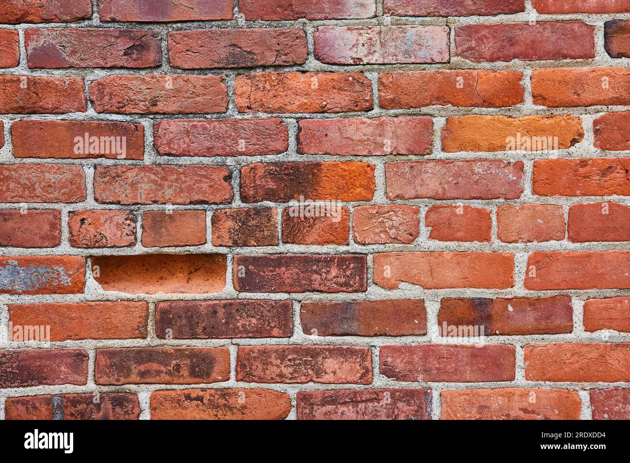Horizontale Ziegelwand mit einem vertieften Ziegel und schmutziger Oberfläche, wobei die mittlere Reihe kleinere Ziegel sind Stockfoto