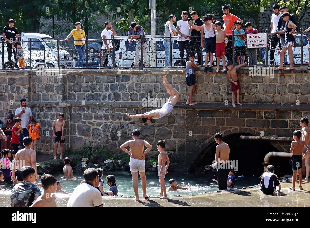 Ein hitzebefallener Teenager springt aus einer Höhe in den historischen Grundwasserpool Anzele in Diyarbakir, eine der heißesten Städte der Türkei, im Südosten der Türkei. Die extreme Hitzewelle aus Nordafrika hat die gesamte Türkei getroffen. Die Wetterbehörden gaben eine Hitzewarnung für 40 Provinzen aus. In den meisten Teilen der Türkei liegt die Lufttemperatur 5-10 Grad über den saisonalen Normen. Die Temperatur, die 40 Grad im Schatten erreicht, liegt bei etwa 50 Grad in der Sonne. Während die Strände voll sind in Städten mit Meeresstränden, versuchen die Leute sich abzukühlen, indem sie die W betreten Stockfoto