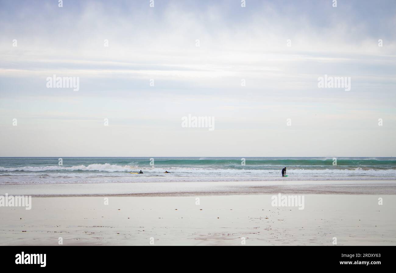 Spaziergänge am breiten Strand der Biscayne Bay, Spanien. Surfstrand mit Leuten. Aktives Lifestyle-Konzept. Unbekannte Leute, die am Strand spazieren gehen. Stockfoto