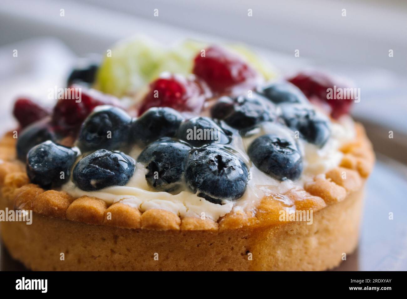 Leckerer Kuchen mit frischen Beeren aus der Nähe. Hausgemachte Torte mit Heidelbeeren, Himbeeren und Kiwischeiben. Köstliches Dessert. Süßes Frühstückskonzept. Stockfoto