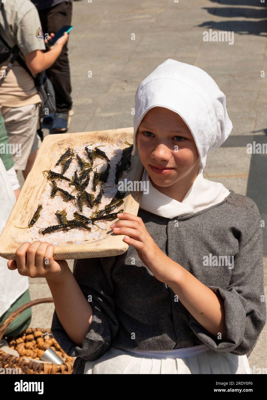 Teenager-Mädchen-Reenactor, mittelalterliche Straßenverkäuferin, die Garnelen im Targ Rybny oder Fischmarkt in der Altstadt von Danzig, Polen, verkauft Stockfoto