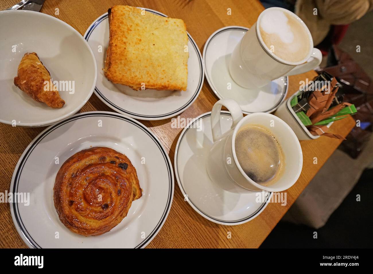 Heißer schwarzer Americano- und Cappuccino-Kaffee mit Croque monsieur, Mini-Croissant und dänischem Brötchen Stockfoto