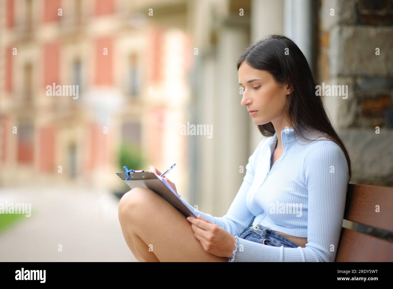 Eine Frau, die auf einer Bank auf der Straße sitzt Stockfoto