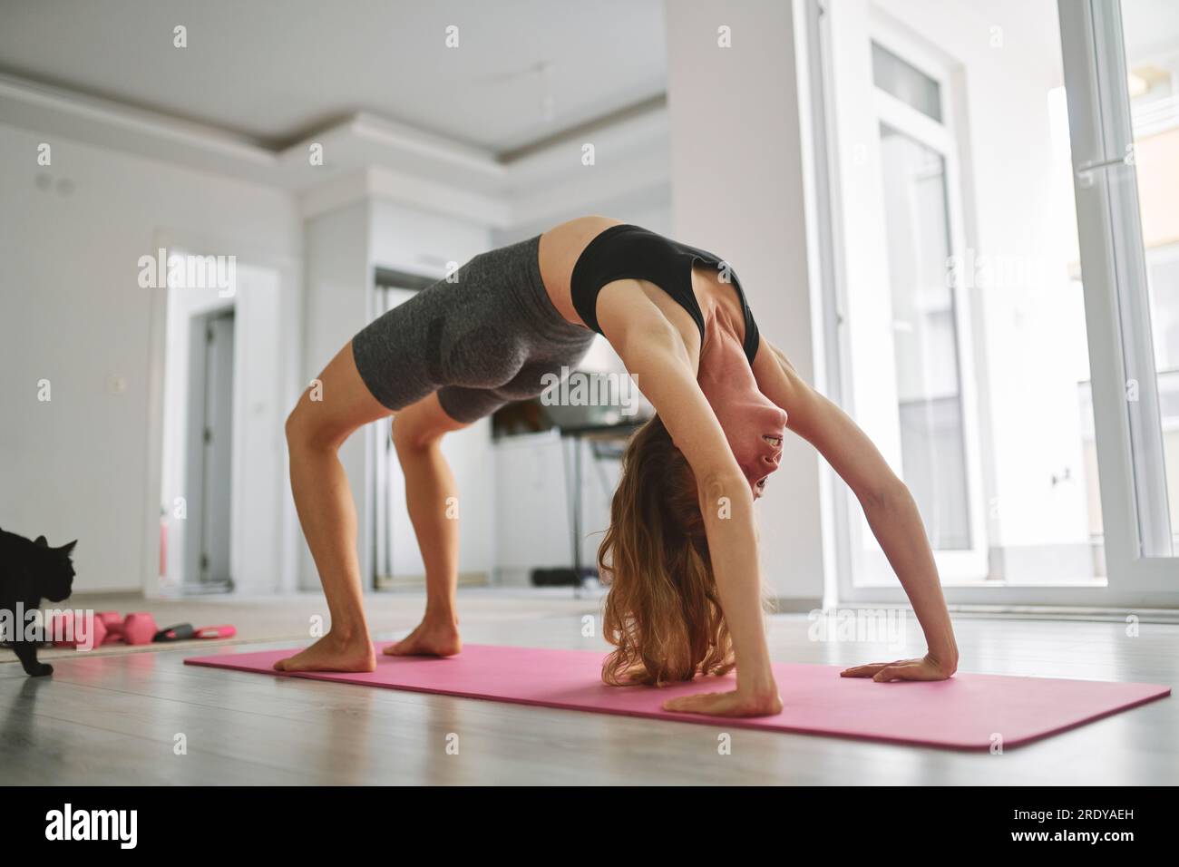 Junge Frau, die zu Hause Yoga auf der Matte praktiziert Stockfoto
