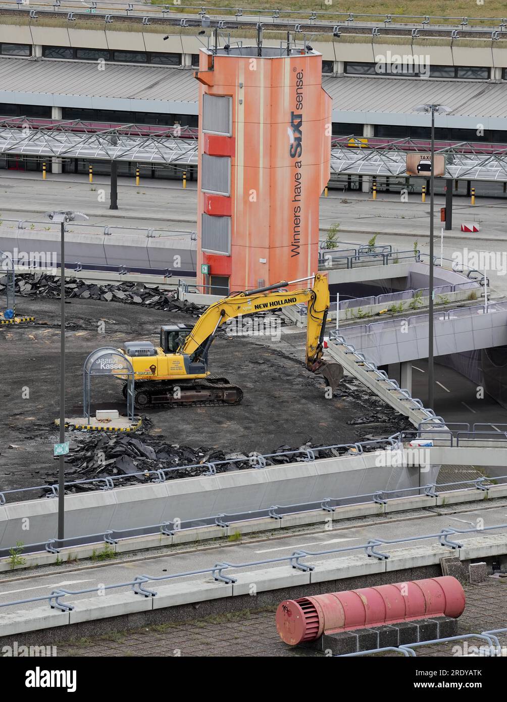 Berlin, Deutschland. 12. Juli 2023. Ein Bagger steht auf dem Parkplatz des ehemaligen Flughafens Berlin-Tegel zwischen den Terminalgebäuden. Auf dem 500 ha großen Gelände befinden sich ein Forschungs- und Industriepark für urbane Technologien, „Berlin TXL - die Urban Tech Republic“, ein Park und das Schumacher-Viertel, ein neues Wohnviertel. Mit der Entwicklung und dem Management wurde das staatliche Unternehmen Tegel Projekt GmbH beauftragt. Kredit: Soeren Stache/dpa/Alamy Live News Stockfoto