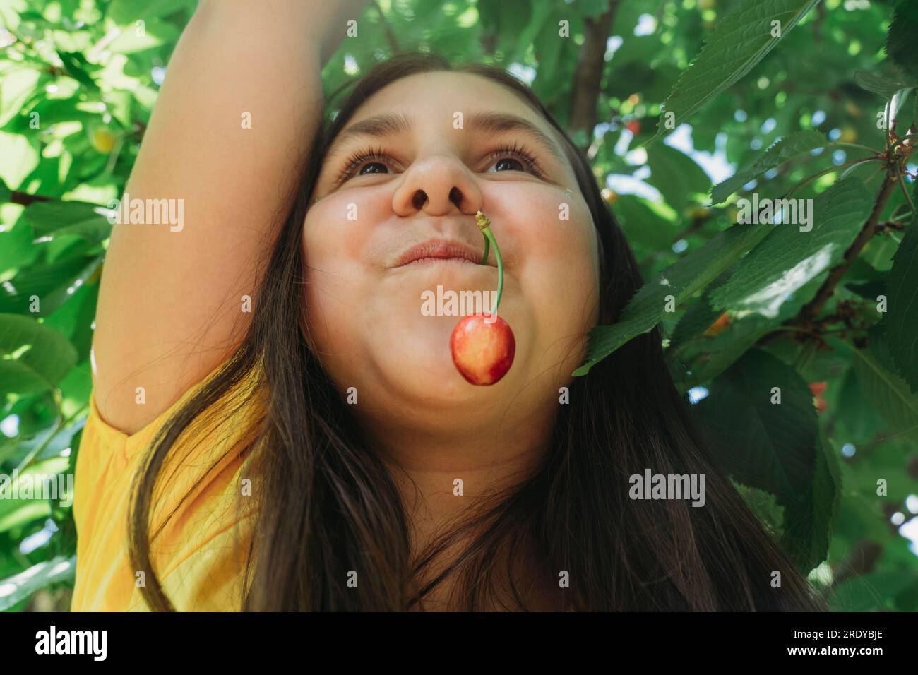Glückliches Mädchen mit Kirsche im Mund Stockfoto
