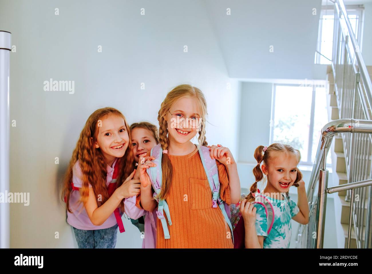 Lächelnde Schulmädchen mit Rucksack, die an der Schultreppe stehen Stockfoto