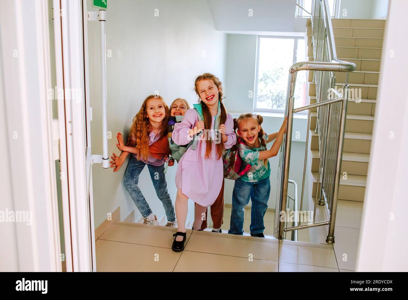 Fröhliche Schulmädchen stehen in der Pause auf der Treppe Stockfoto