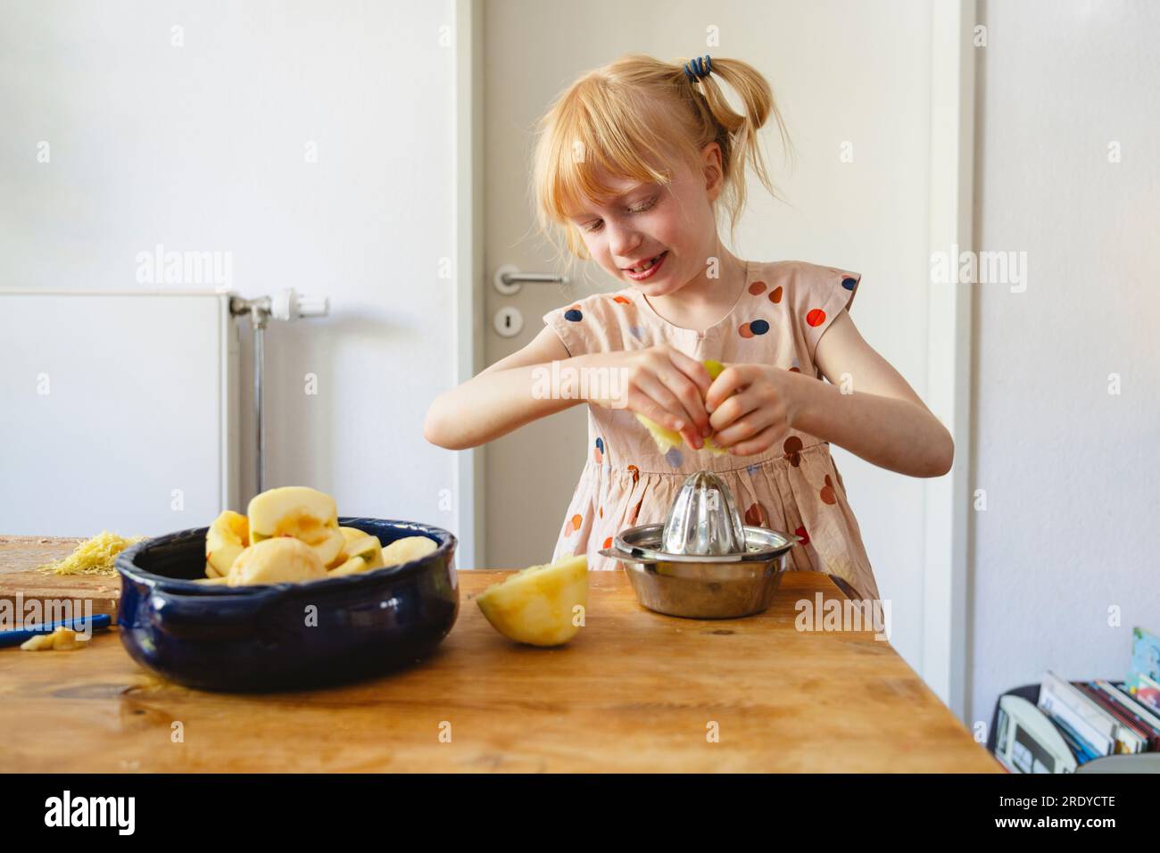 Ein Mädchen, das zu Hause Zitrone mit dem Entsafter ausdrückt Stockfoto