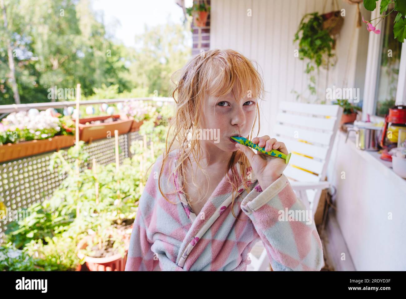 Blondes Mädchen, das Zähne putzt, steht auf dem Balkon Stockfoto