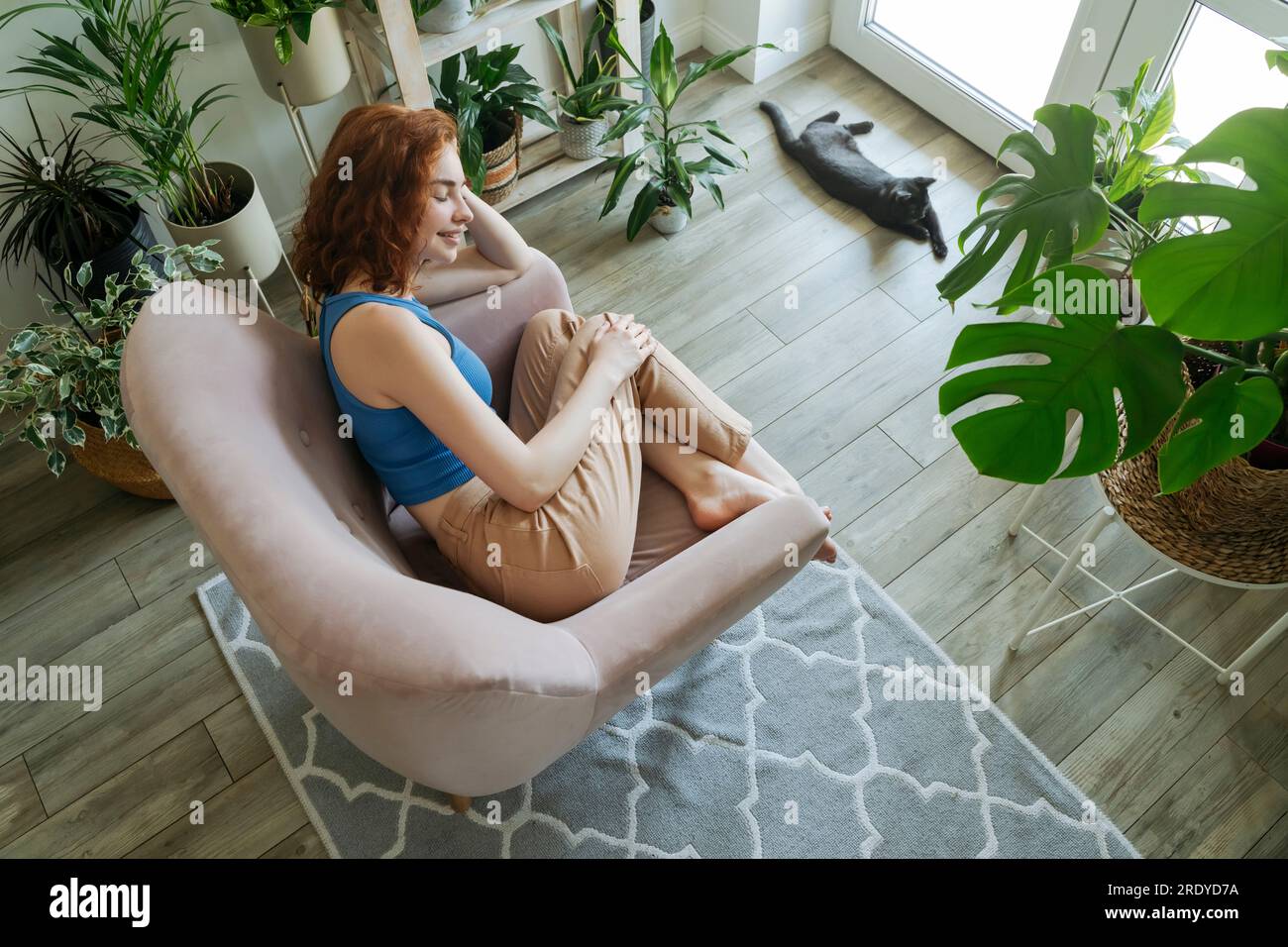 Glückliche Frau, die sich zu Hause im Sessel entspannt Stockfoto