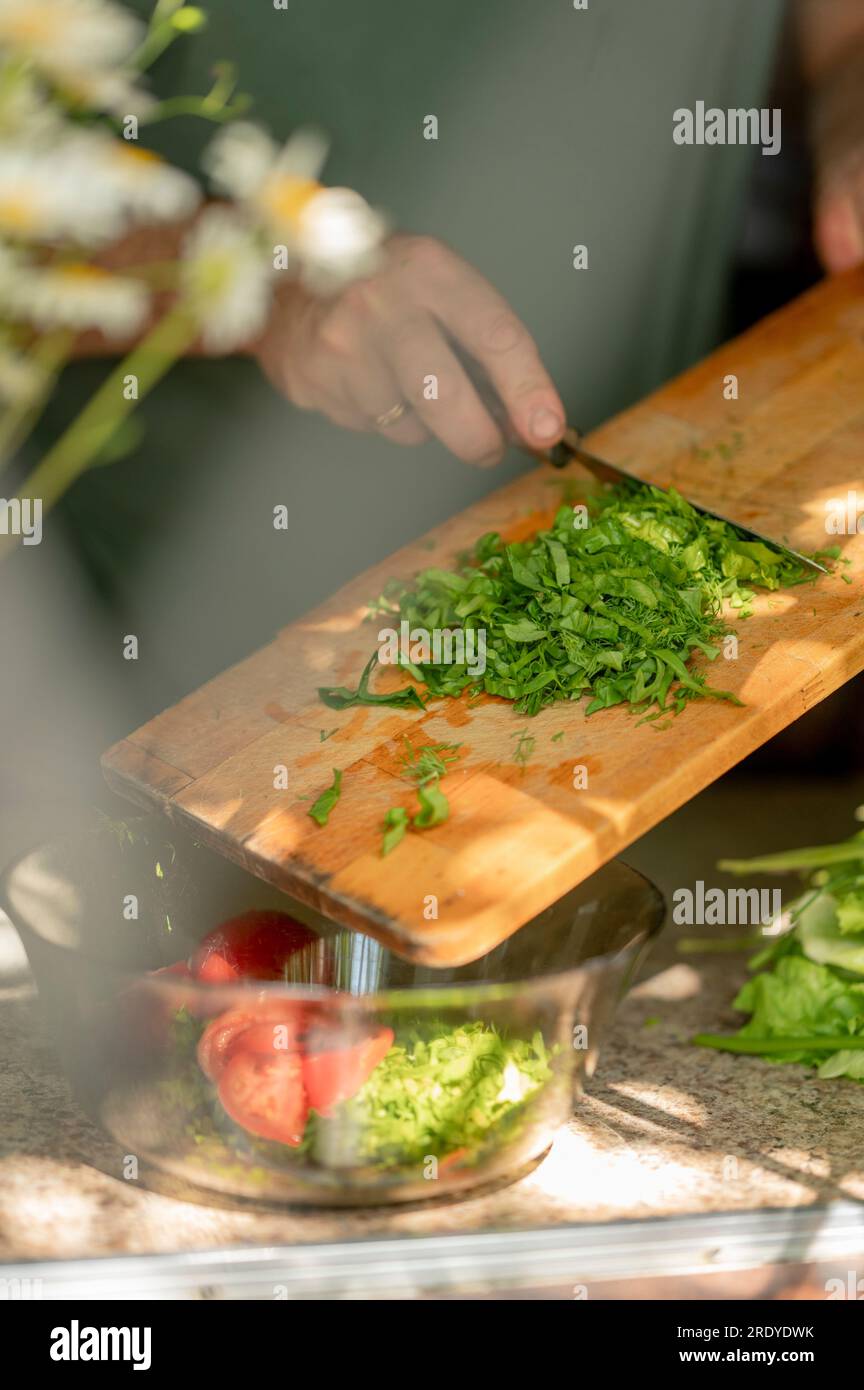 Mann, der zu Hause gehacktes Grün in die Schüssel gibt Stockfoto