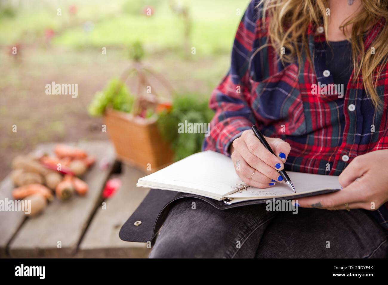 Junge Frau, die mit Stift Tagebuch schreibt Stockfoto