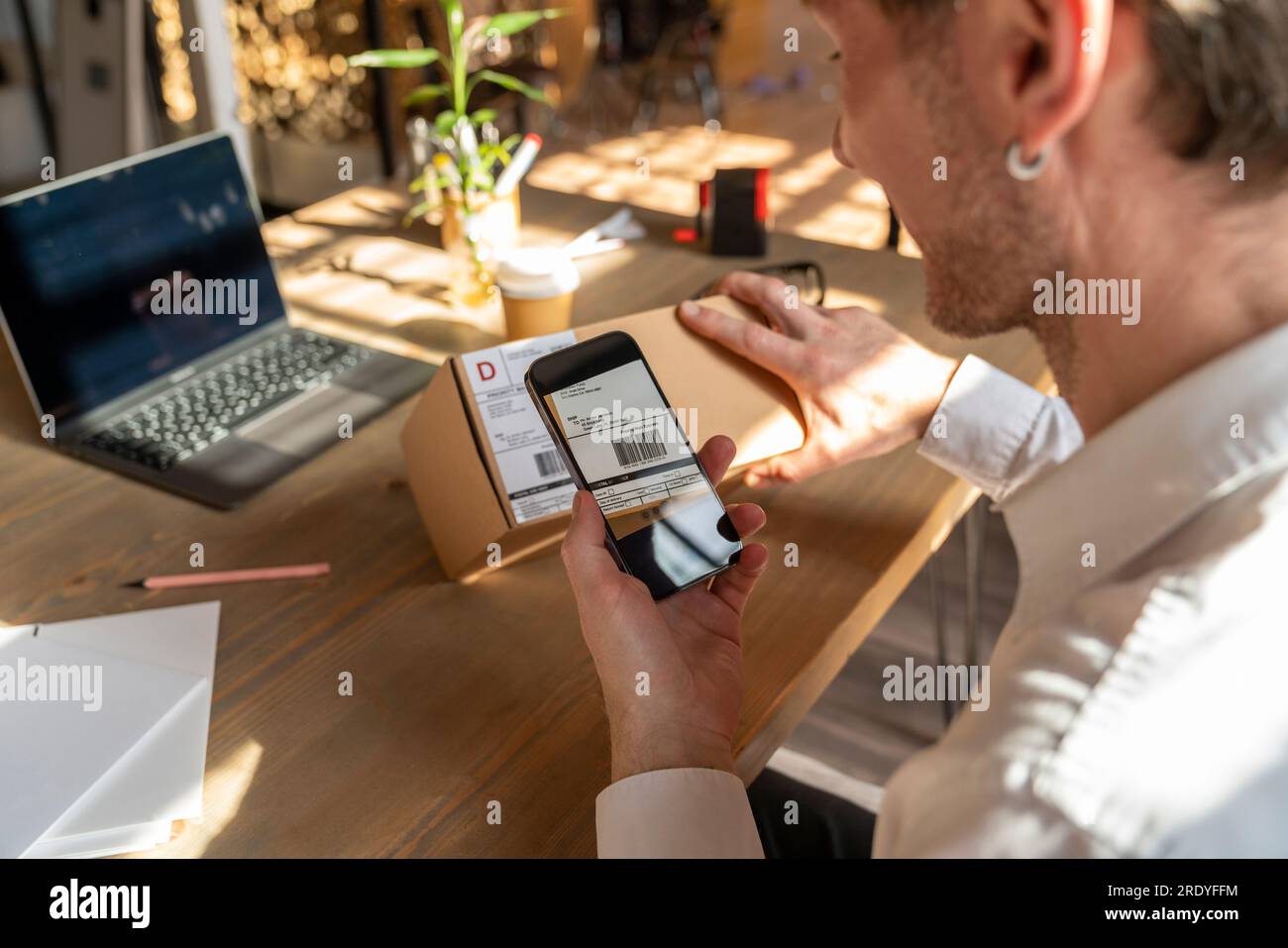 Geschäftsmann scannt den Barcode auf dem Paket über die Smartphone-App Stockfoto