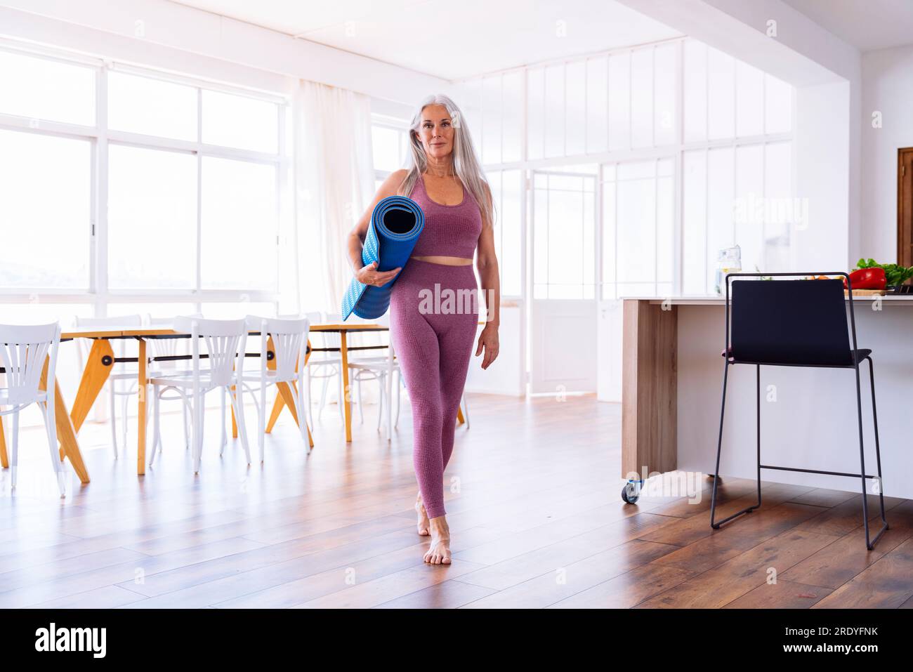 Eine Frau mit Yoga-Matte, die zu Hause läuft Stockfoto
