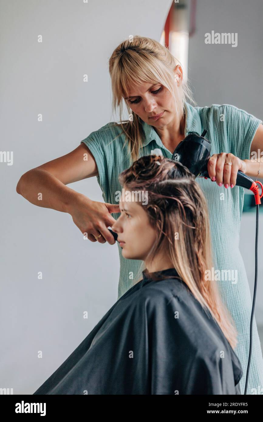 Friseur trocknet die Haare des Kunden im Salon Stockfoto