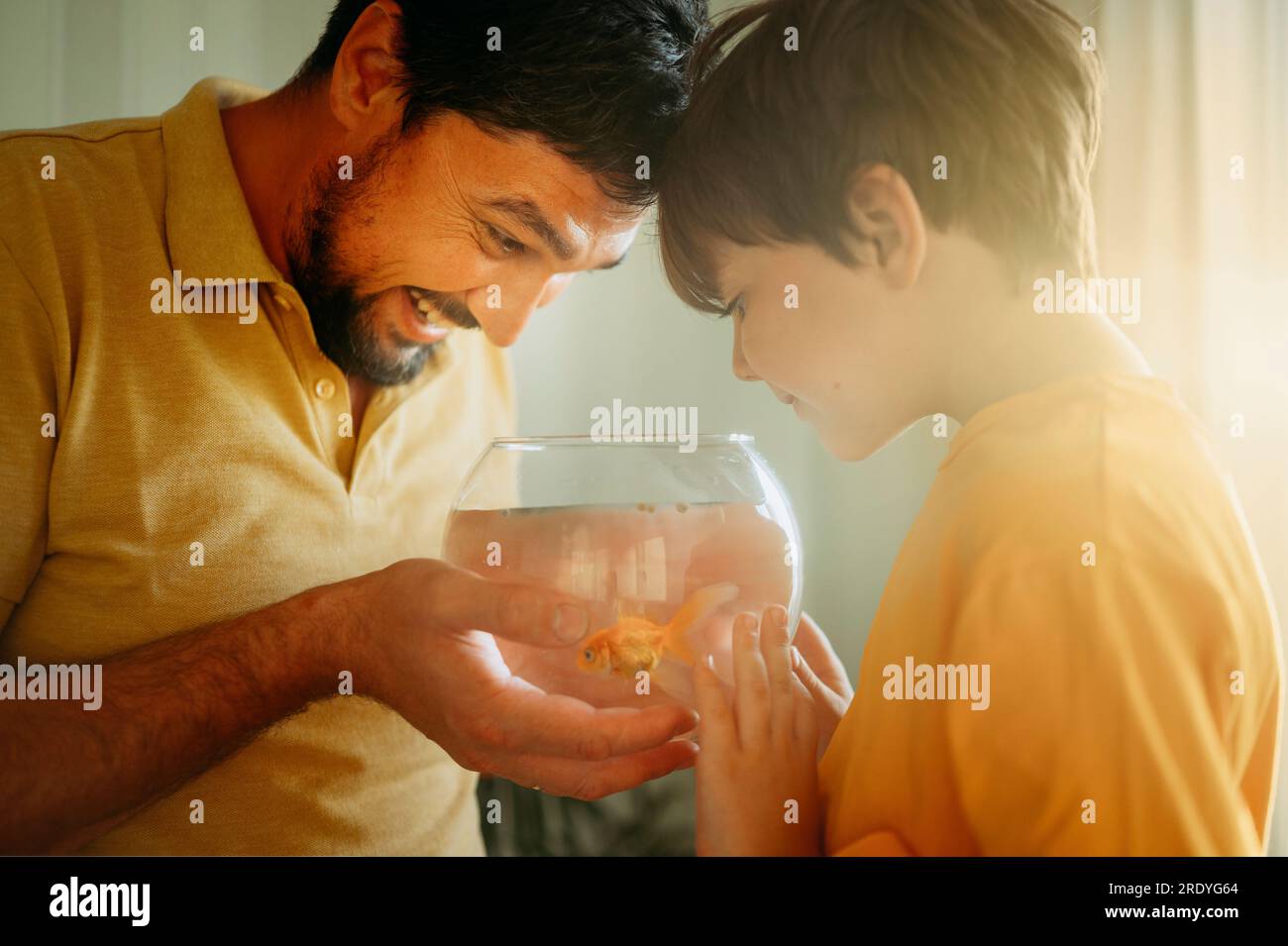 Ein Junge mit glücklichem Vater, der Fischglas hält Stockfoto